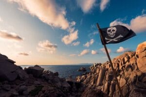 Un drapeau de pirate flotte sur la côte au coucher de soleil